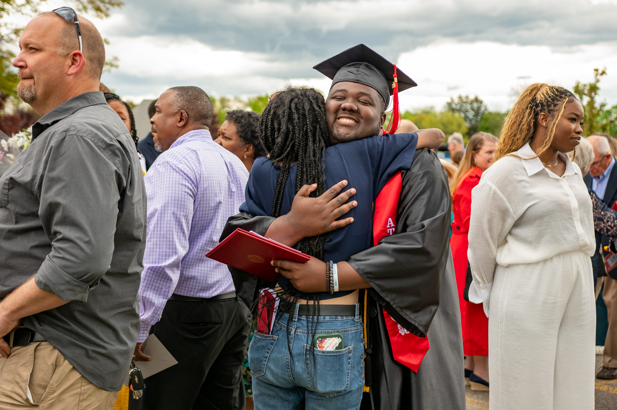 A graduate in a cap and gown hugs a loved one at Roberts Wesleyan University's commencement ceremony