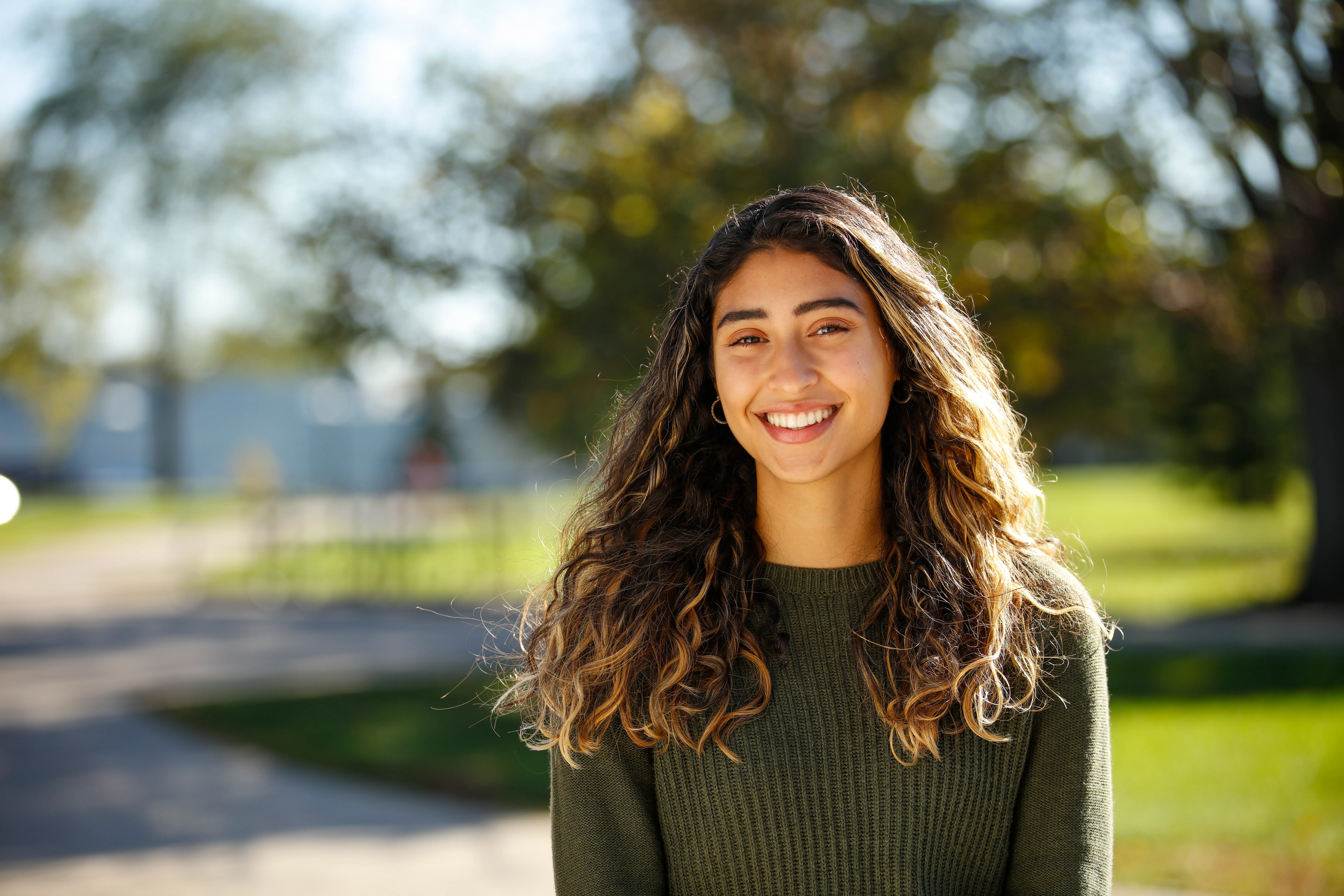A young woman sits outside and smiles
